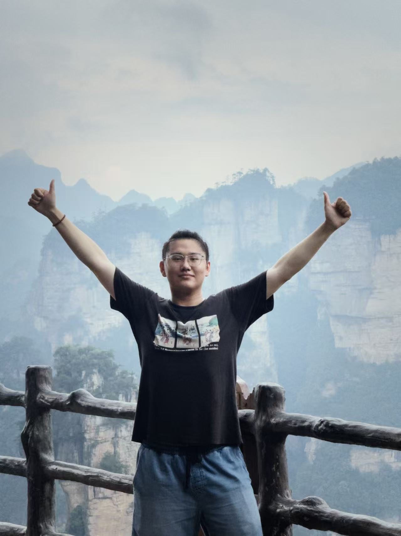 Jesse Liu raising both arms in the mountains